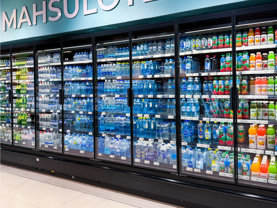 Refrigerated grocery display with bottled drinks and colorful beverages behind glass doors