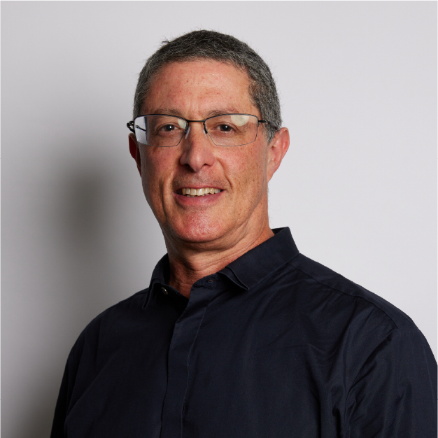 Portrait of a smiling man in glasses wearing a dark shirt against a light gray background