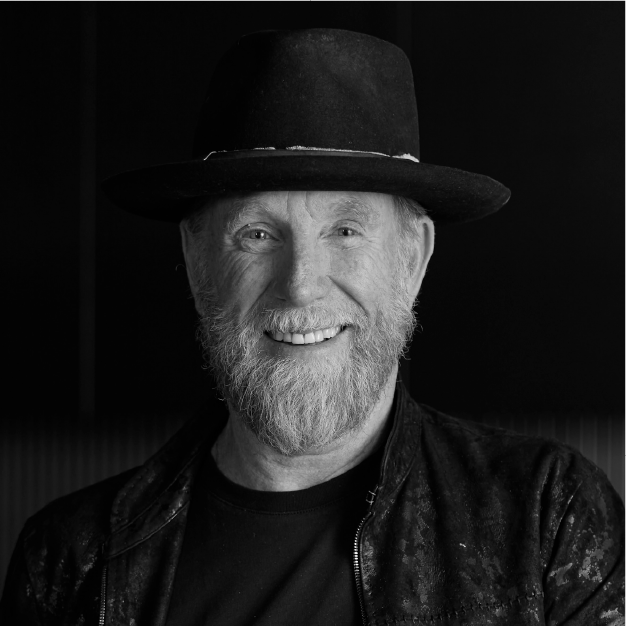 Smiling bearded man in a black hat and jacket against a dark background