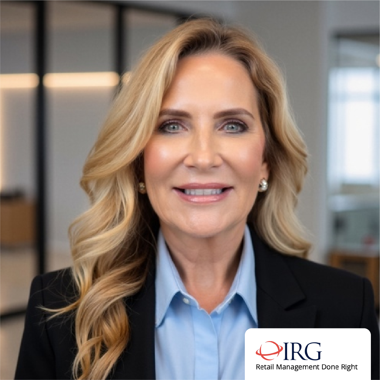 Professional woman in a black blazer and blue shirt smiling in a modern office setting