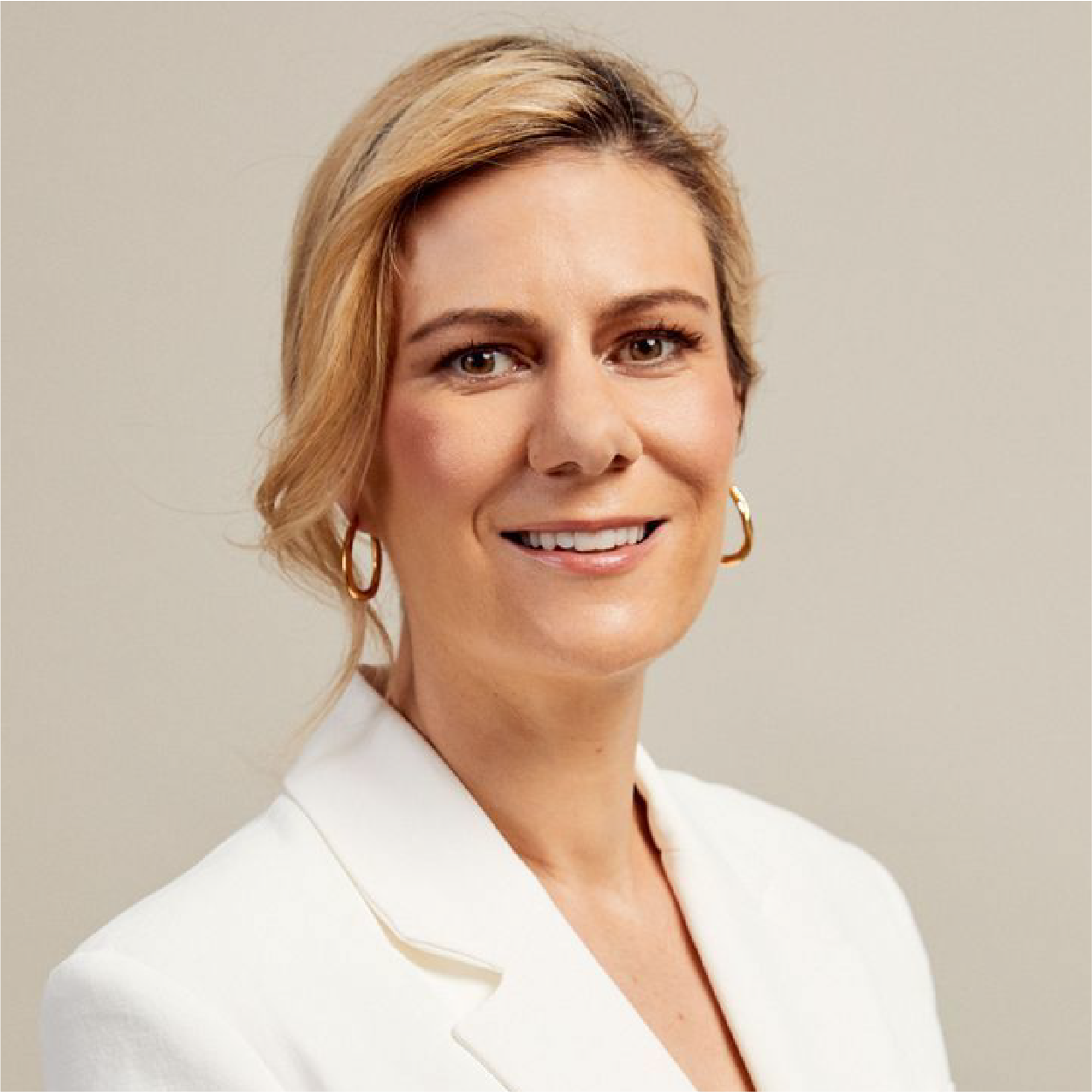 Smiling woman in a white blazer against a neutral background