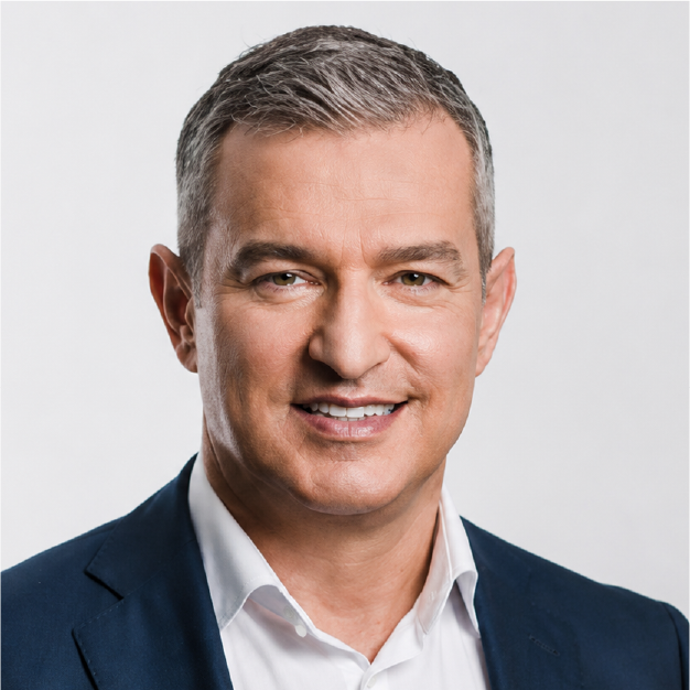 Studio headshot of a smiling man in a navy suit and white shirt on a light gray background