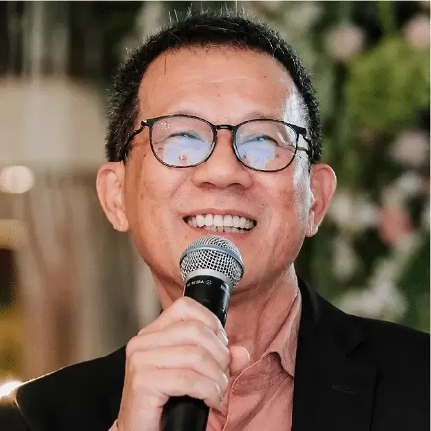 Smiling man in glasses speaking into a microphone at an event