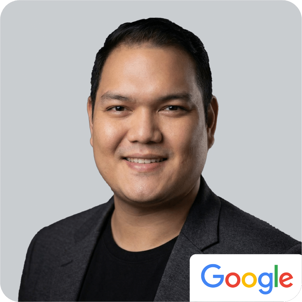 Smiling person in a dark blazer with a Google logo in the corner