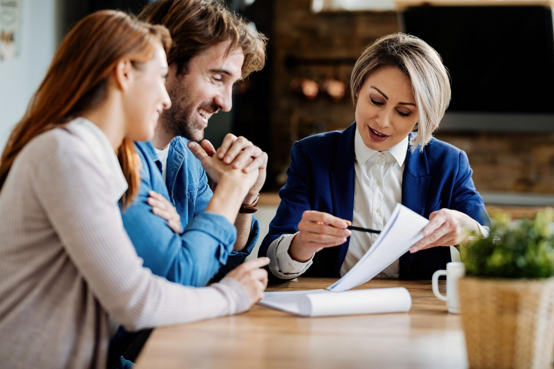 A woman is sitting at a table talking to a man and woman.