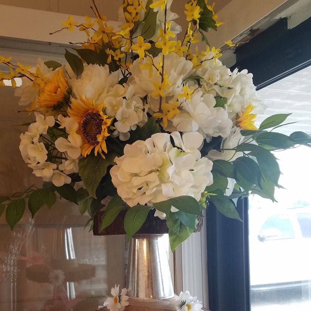 A vase filled with white flowers and yellow flowers