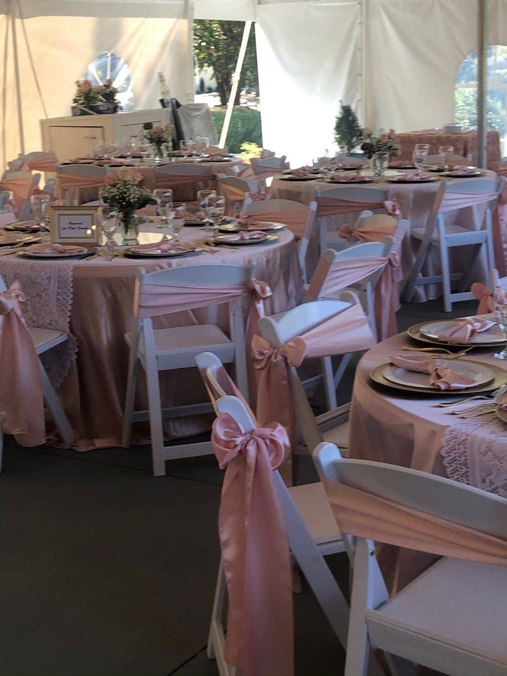 A tent with tables and chairs set up for a wedding reception.