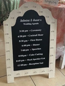 A sign that says `` wedding agenda '' is sitting on a tiled floor.