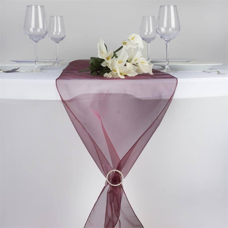 A table with a table runner and flowers on it