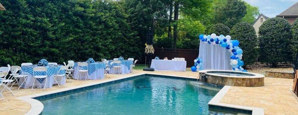 A large swimming pool with tables and chairs around it.