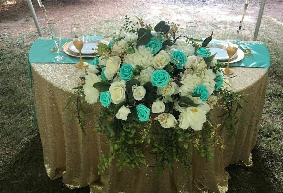 A table with a gold tablecloth and flowers on it.