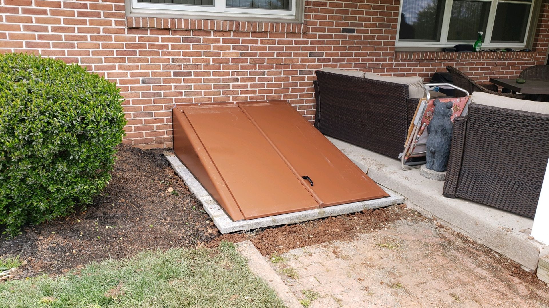 A brown door is sitting on the side of a brick building.