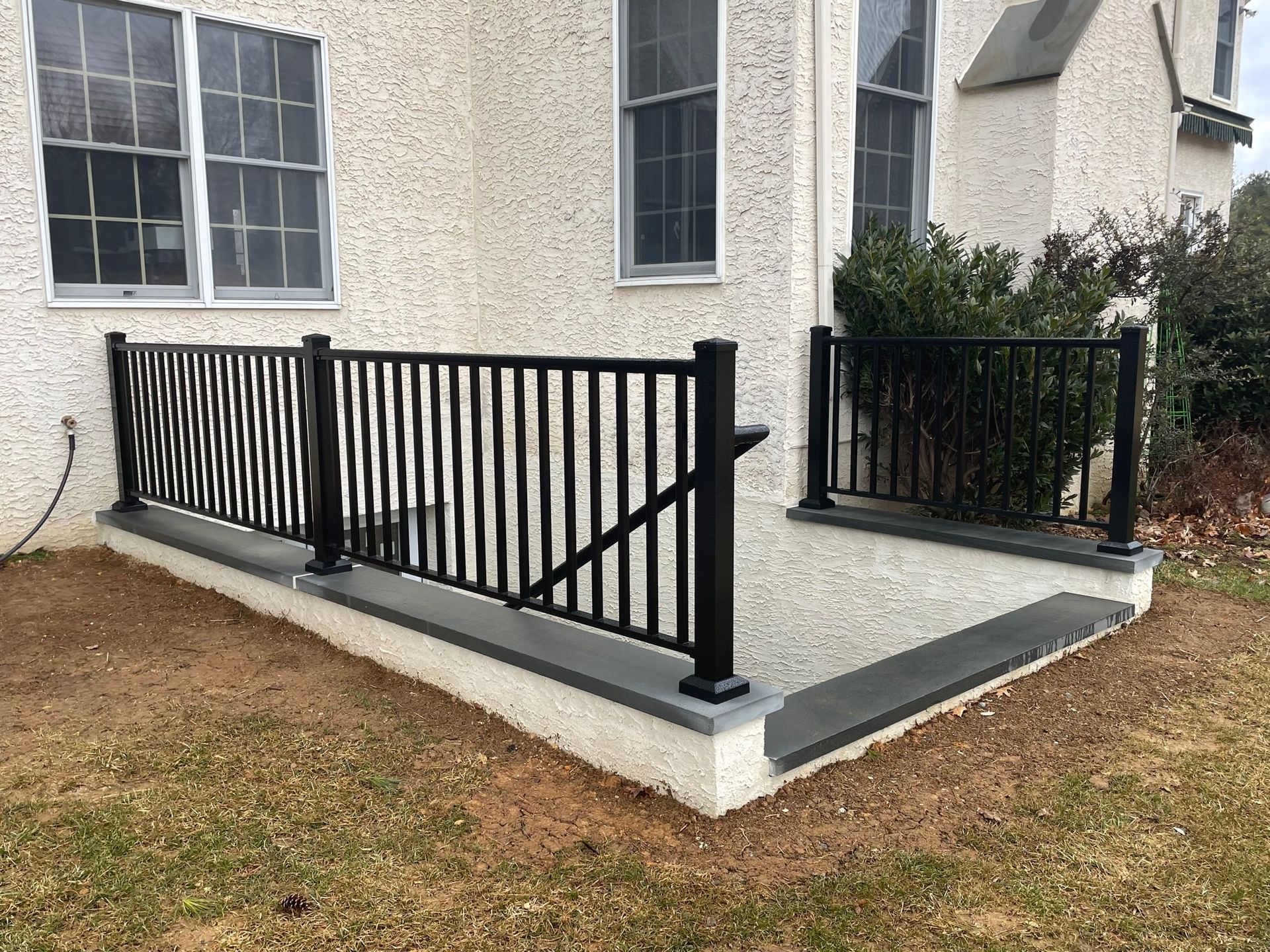Accessible ramp with black metal railings beside a house porch