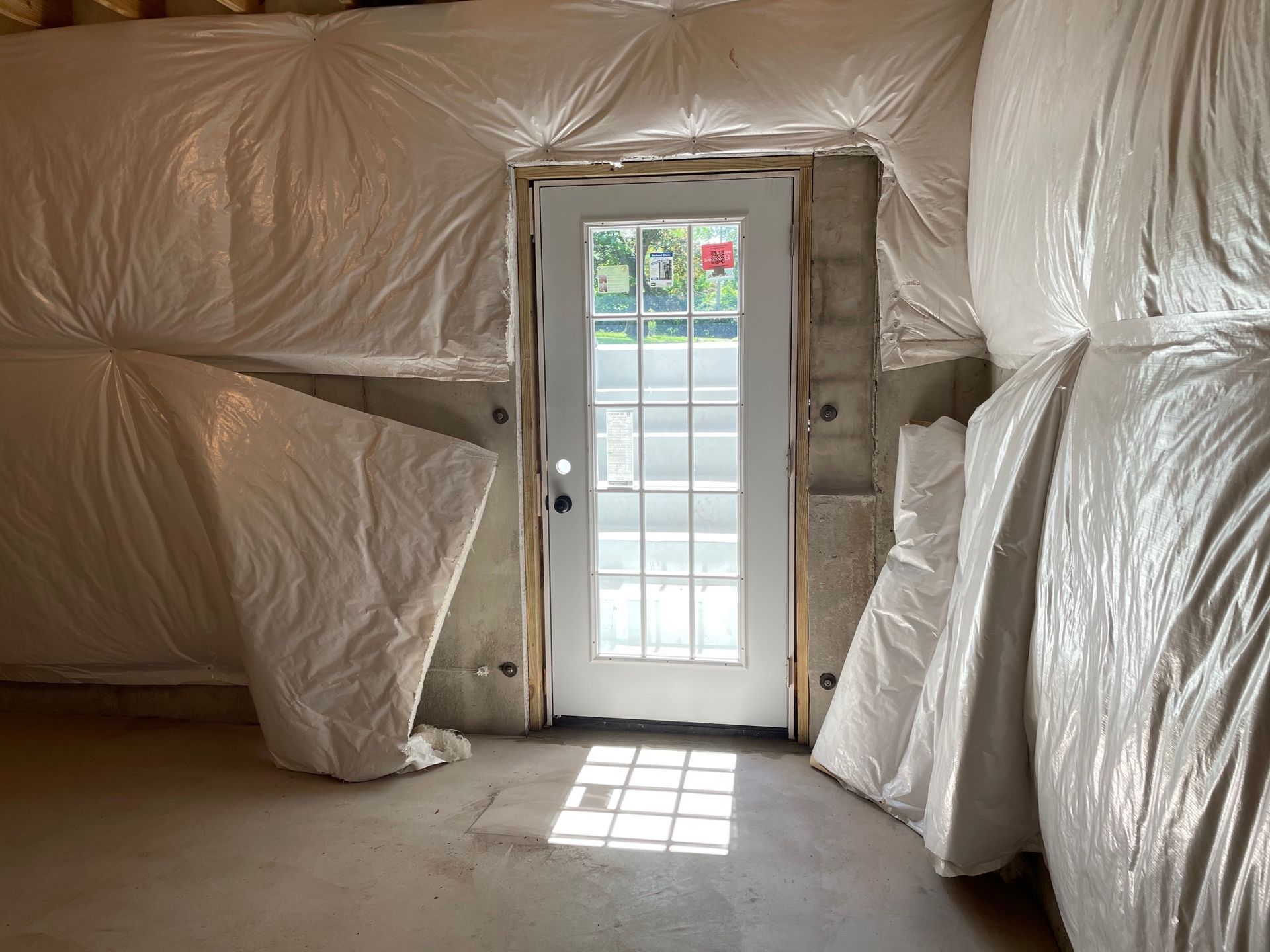 A room with a door and walls covered in plastic.