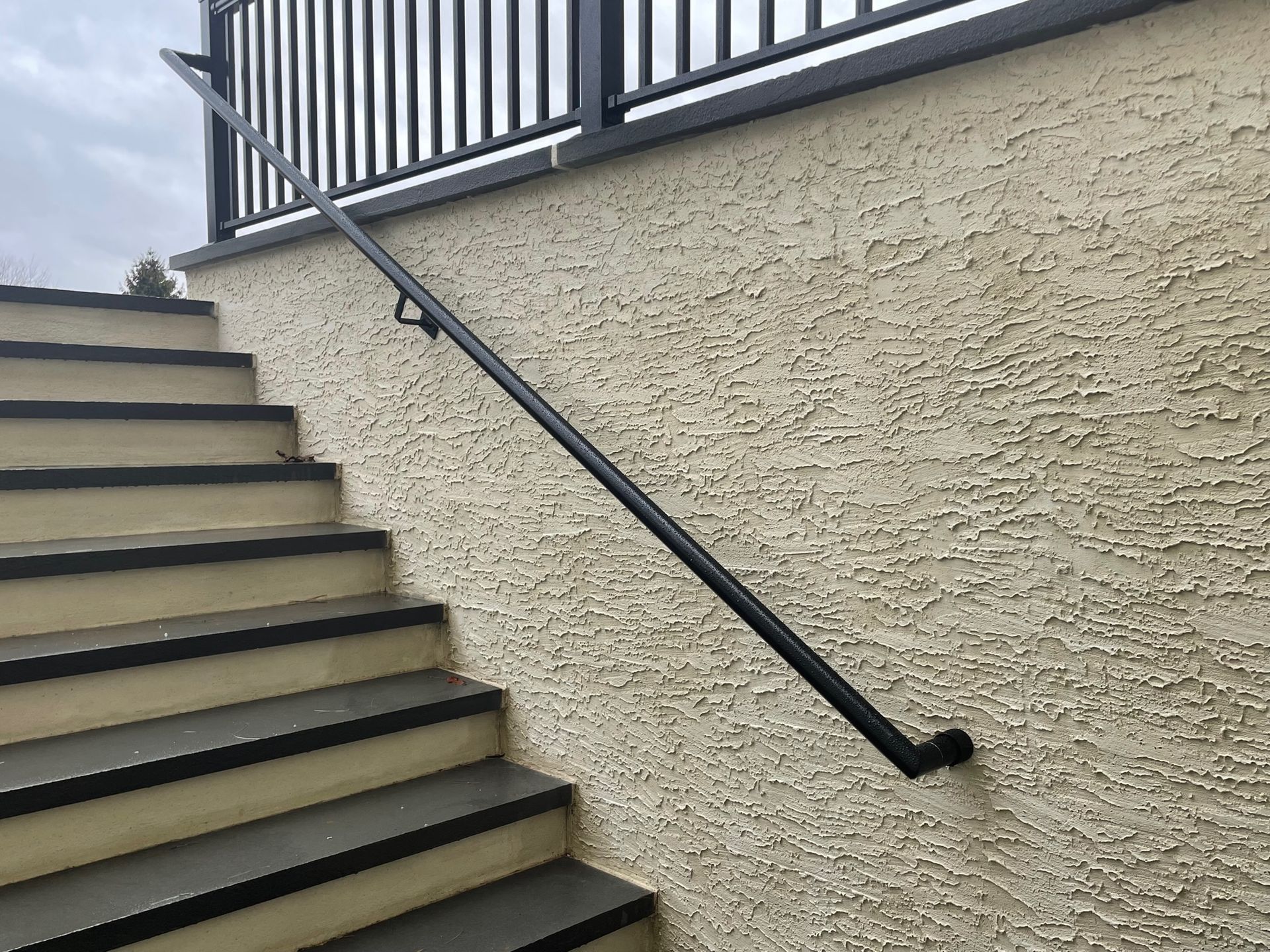 A set of stairs with a black railing on the side of a building.