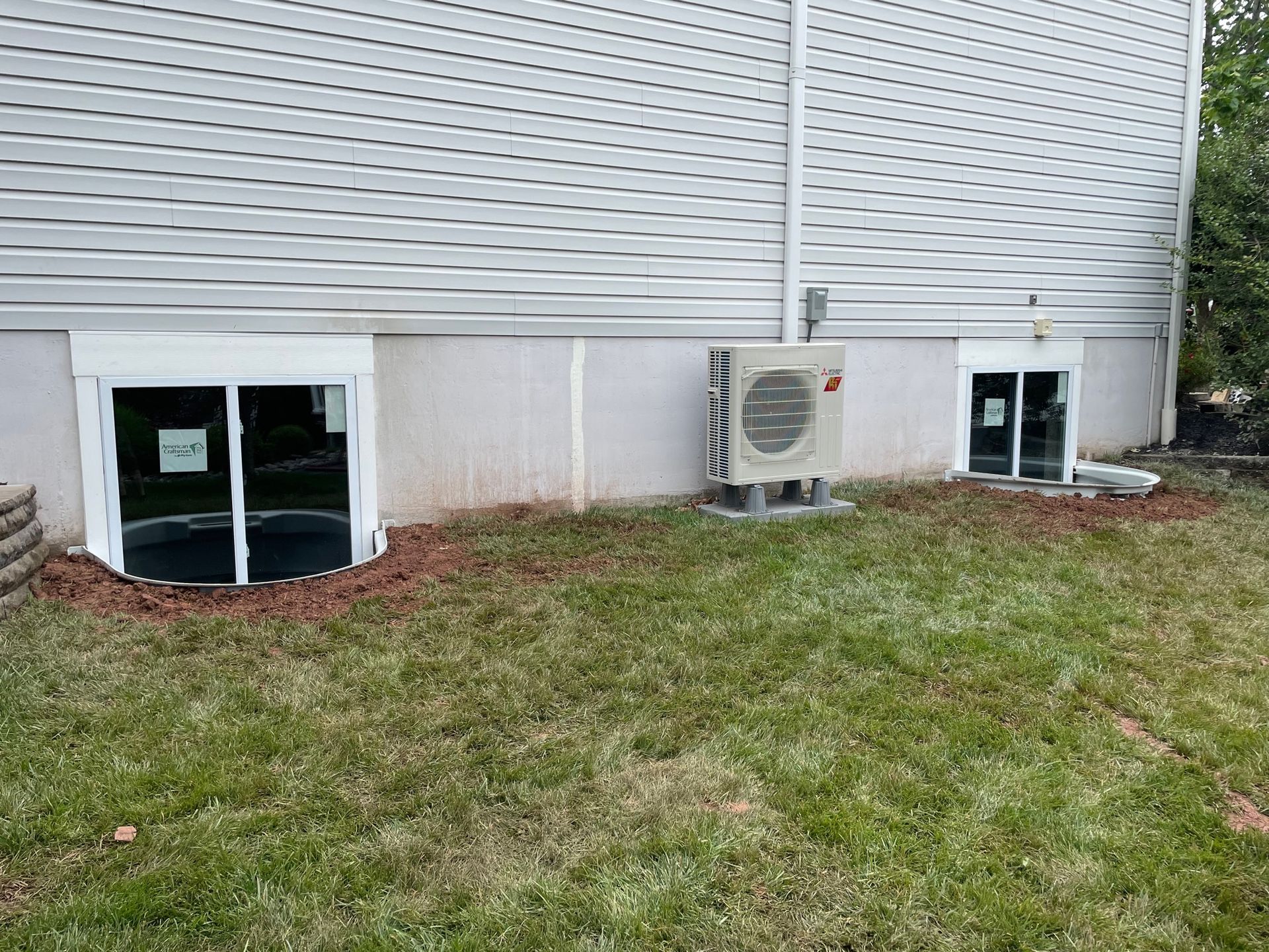 There are two air conditioners in the backyard of a house.