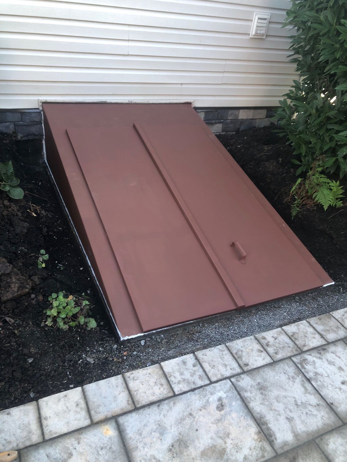 A brown door is sitting on a sidewalk next to a house