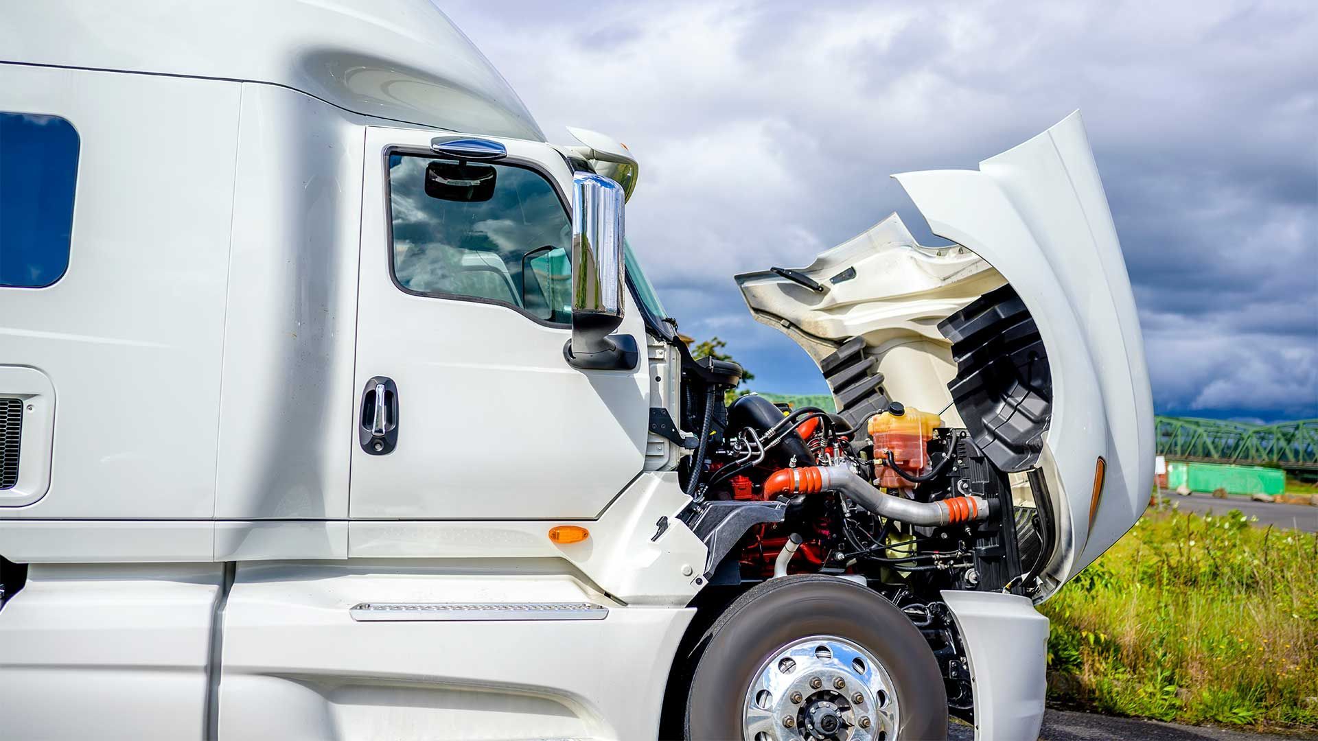 A semi truck with its hood open is parked on the side of the road.