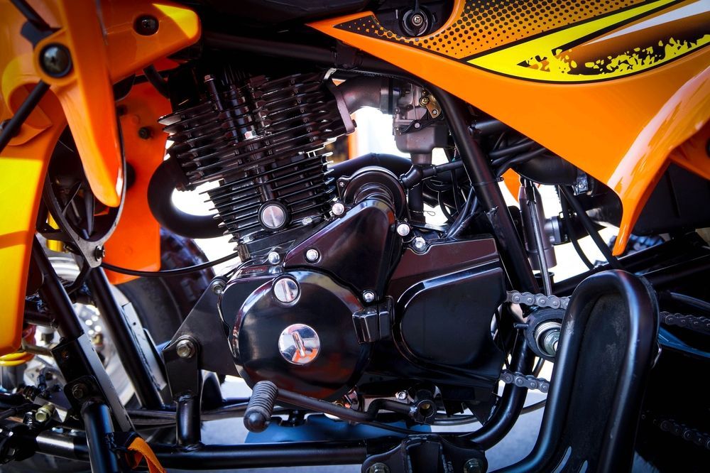 Close-up of a black motorcycle engine beneath orange fairing panels