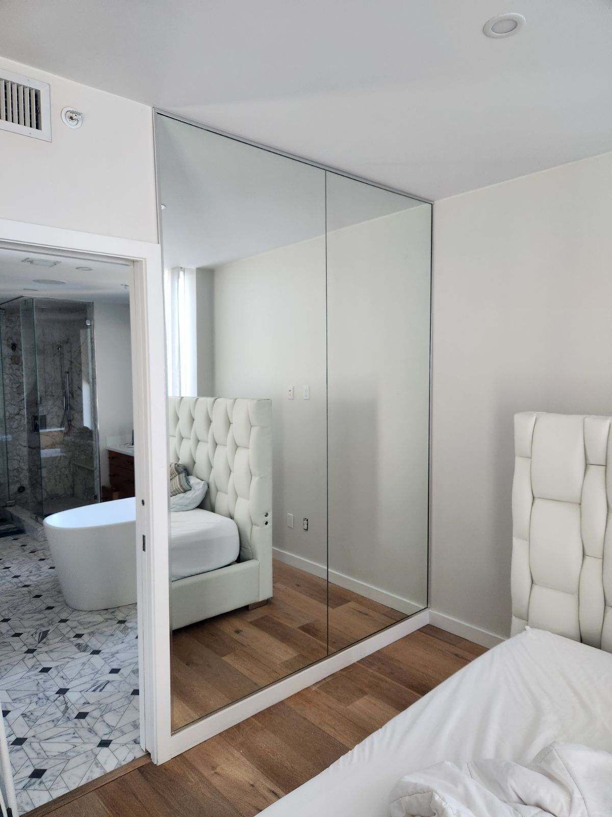 Mirror wall in a bedroom to open and make the space feel bigger in Saint Pete, done by City Glass and Mirror.