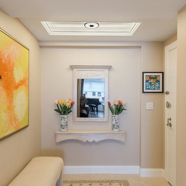 A hallway with two vases of flowers and a mirror