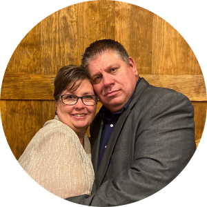 a man and woman are posing for a picture in front of a wooden wall