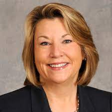 A woman in a black suit is smiling for the camera.