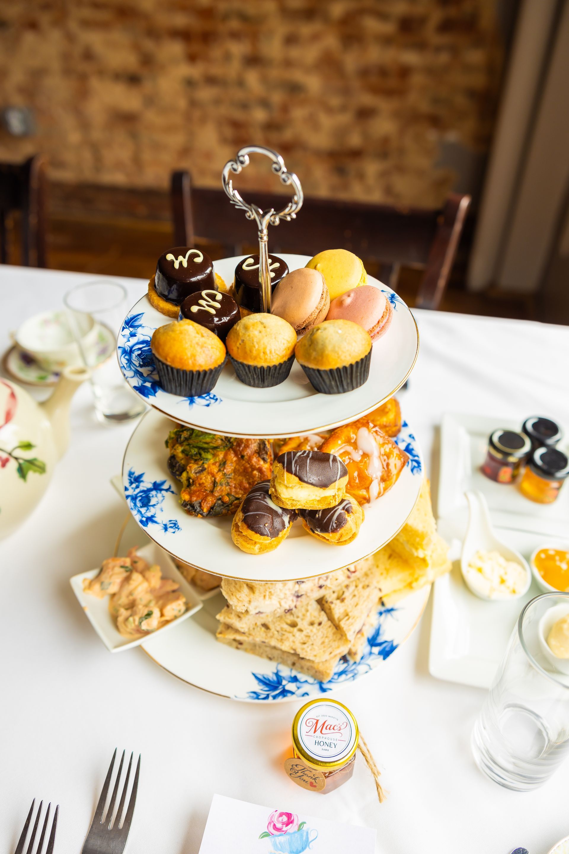 A three tiered cake stand filled with cupcakes and sandwiches on a table.