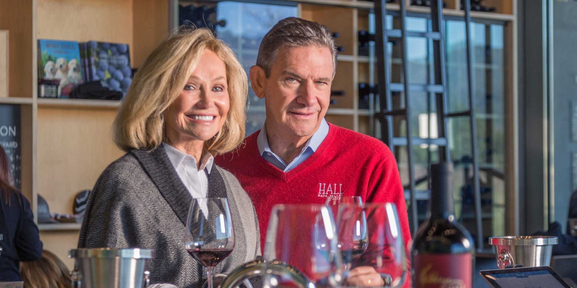 A man and a woman are standing next to each other holding glasses of wine.