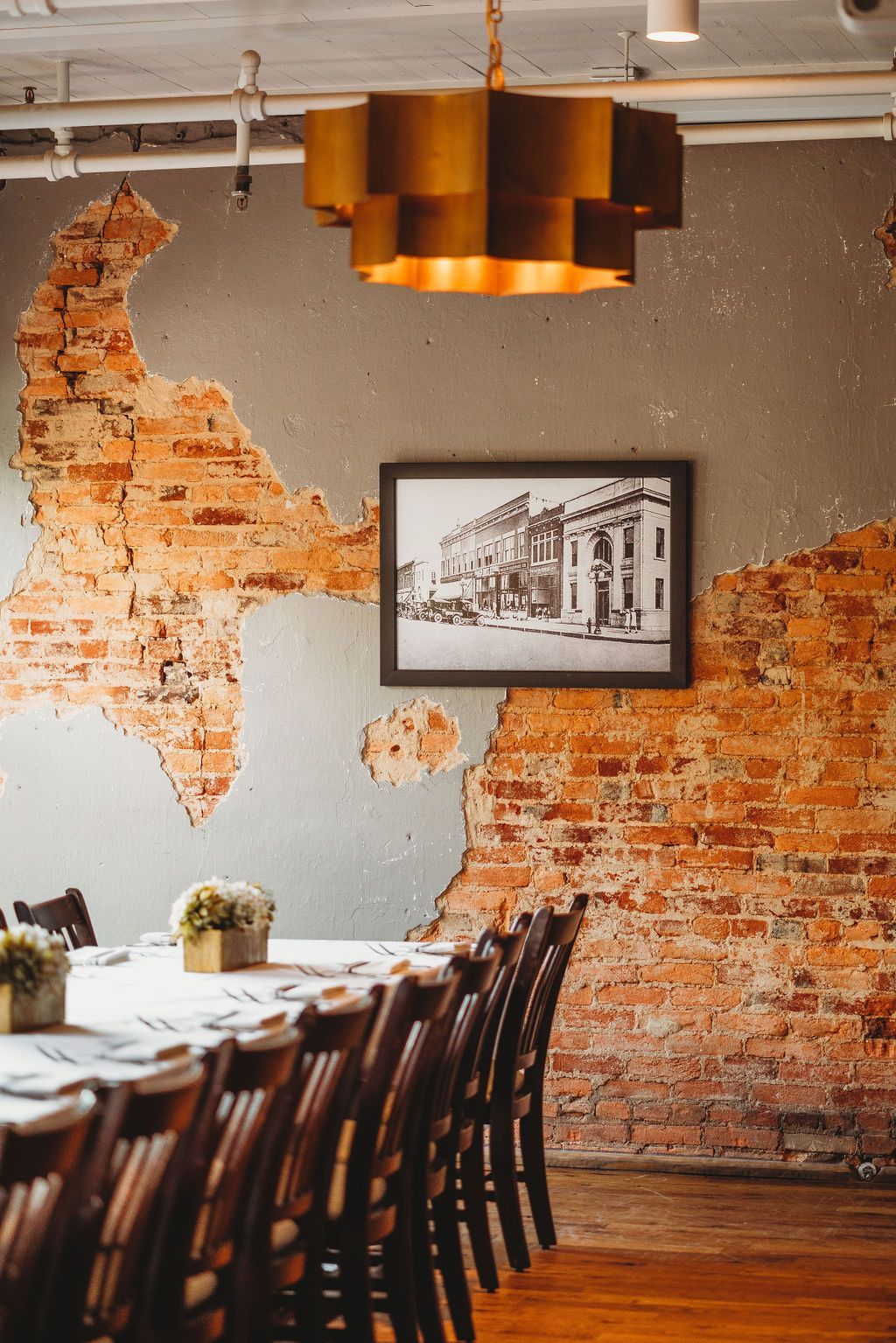 A dining room with a long table and chairs and a brick wall.