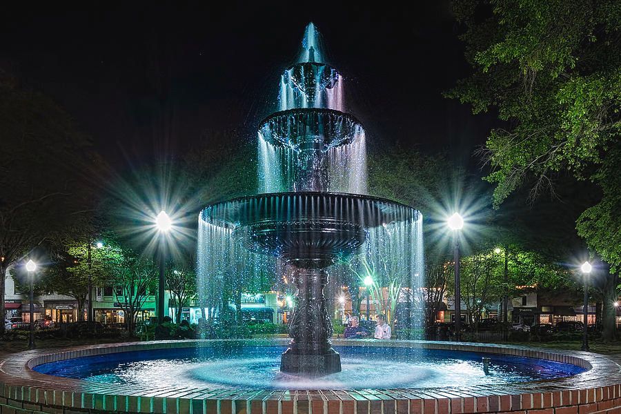 A fountain is lit up at night in a park.