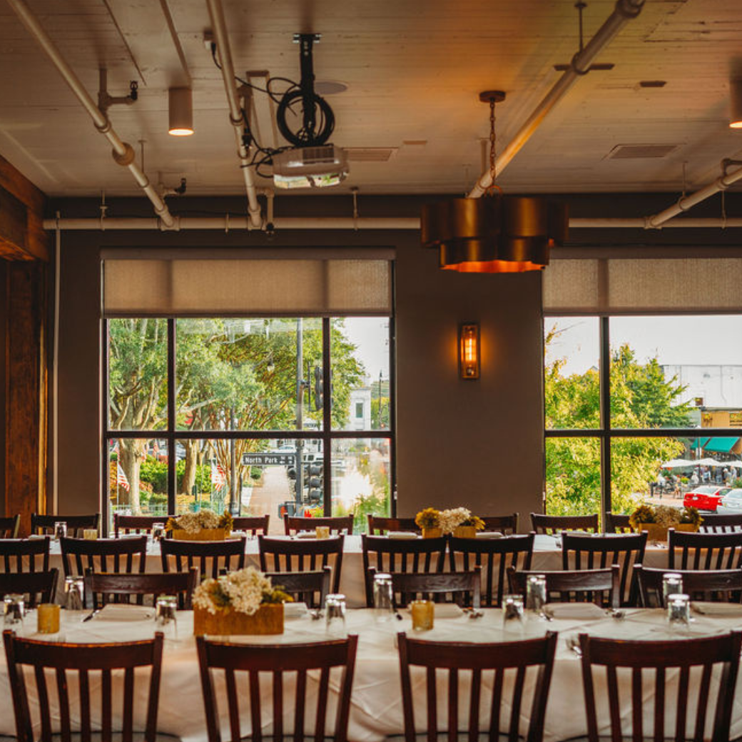 A restaurant with tables and chairs and a projector on the ceiling