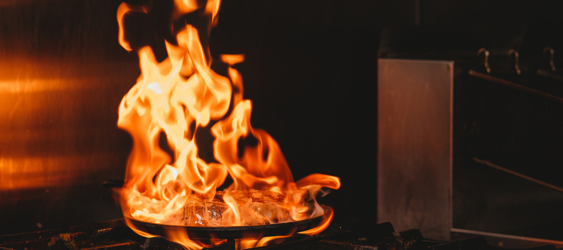 A pan is cooking on a stove with flames coming out of it.