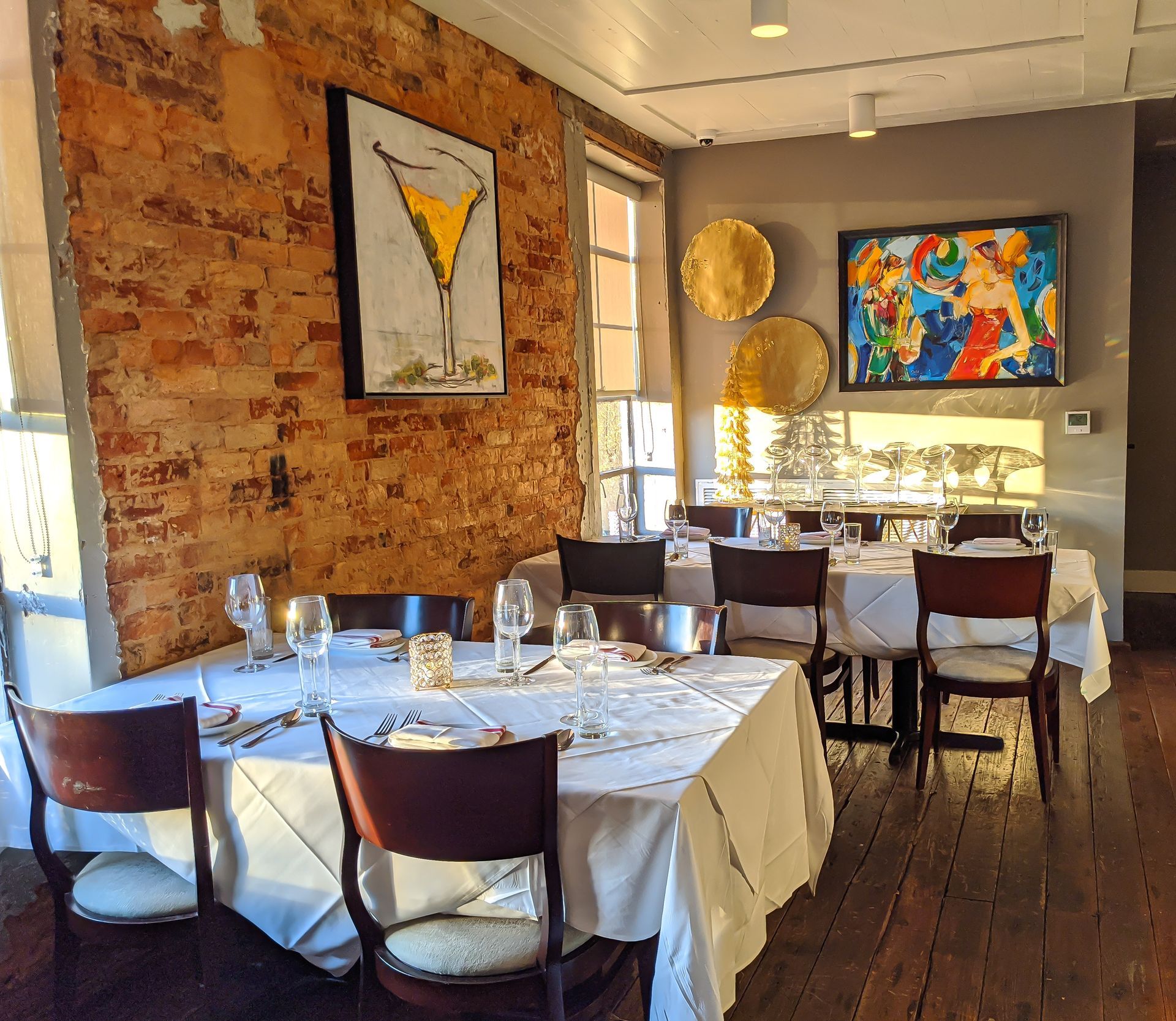 A restaurant with tables and chairs and a painting of a martini glass on the wall