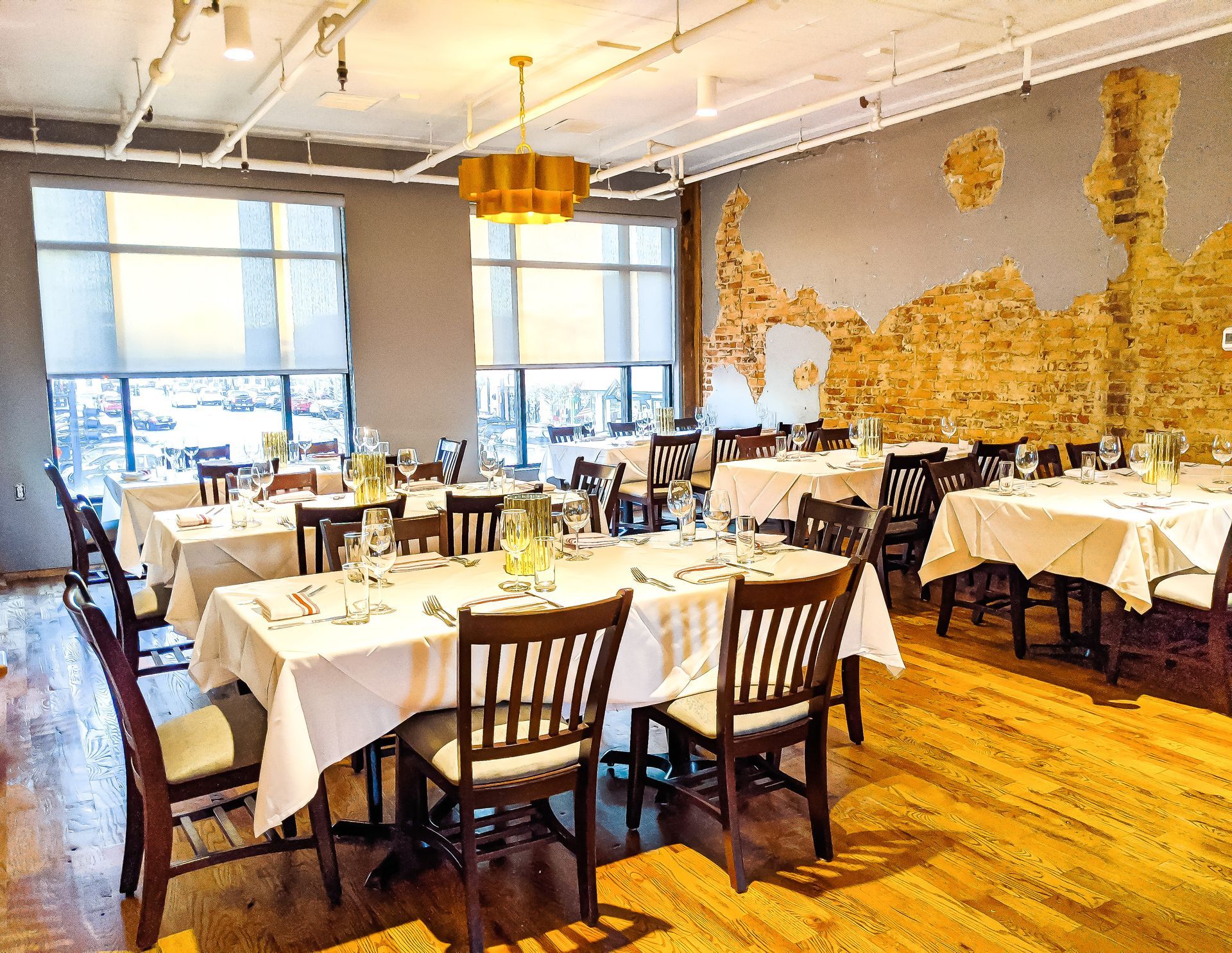 A large dining room with tables and chairs and a brick wall.
