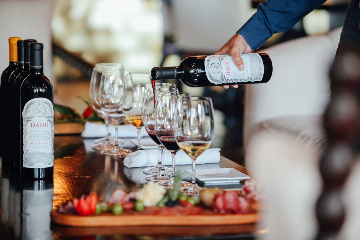 A man is pouring wine into a glass on a table.