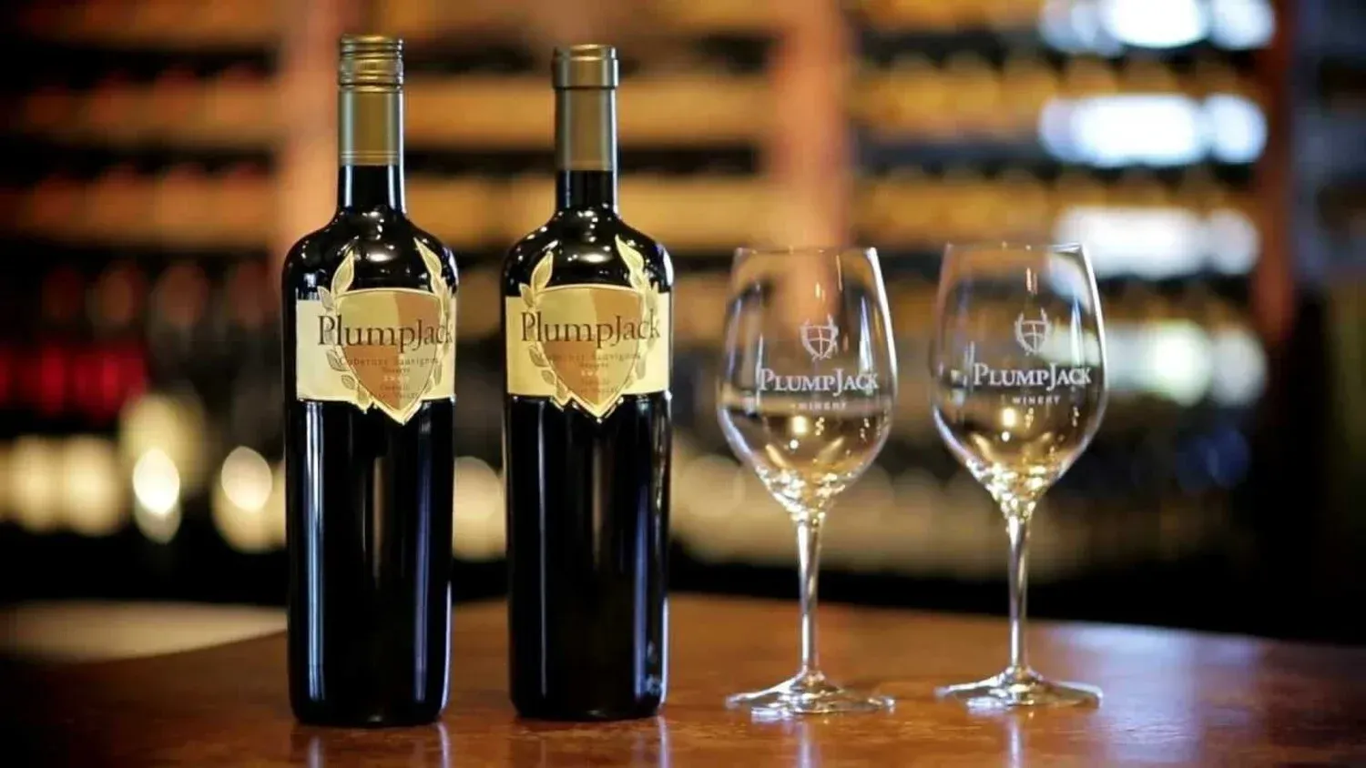 Three bottles of wine and two wine glasses on a table.