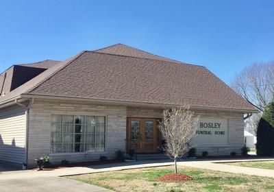 Exterior of a beige building with a brown roof and sign reading “Bosley Funeral Home”
