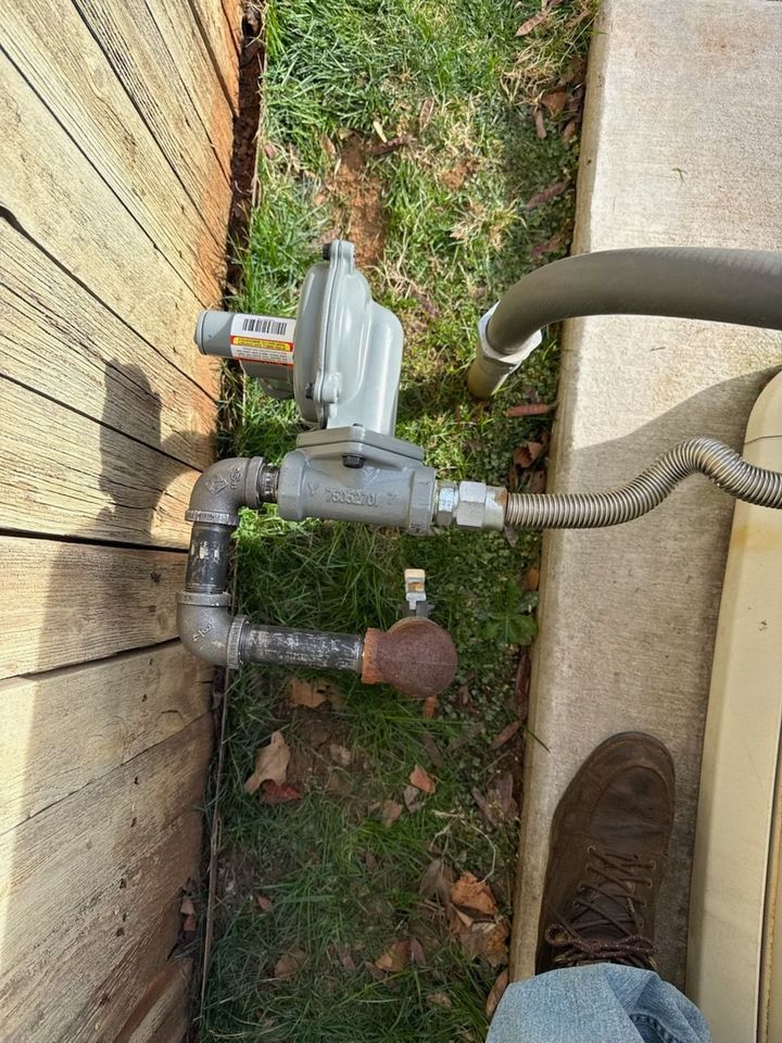 Gas meter and pipes beside a house wall on a patch of grass