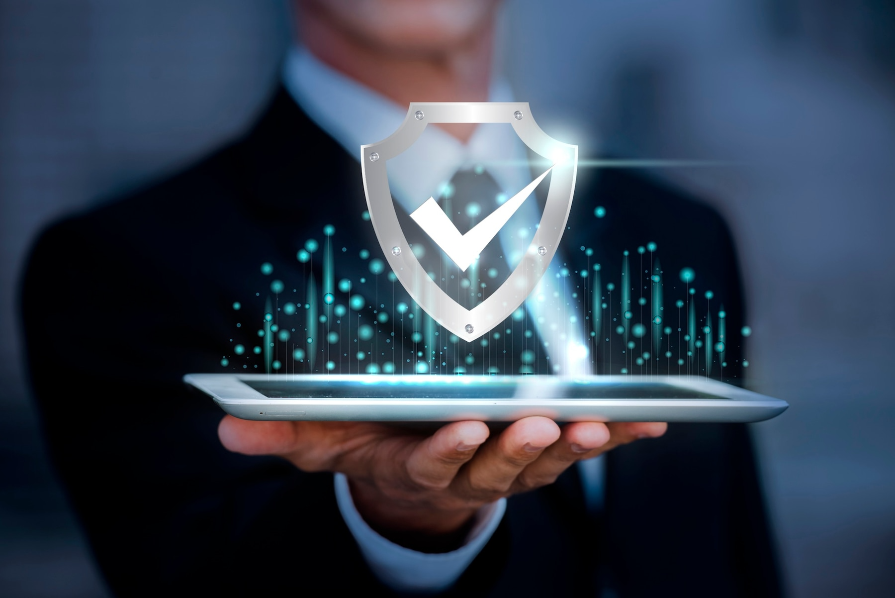 Businessman holding a glowing tablet with a shield and checkmark cybersecurity icon.