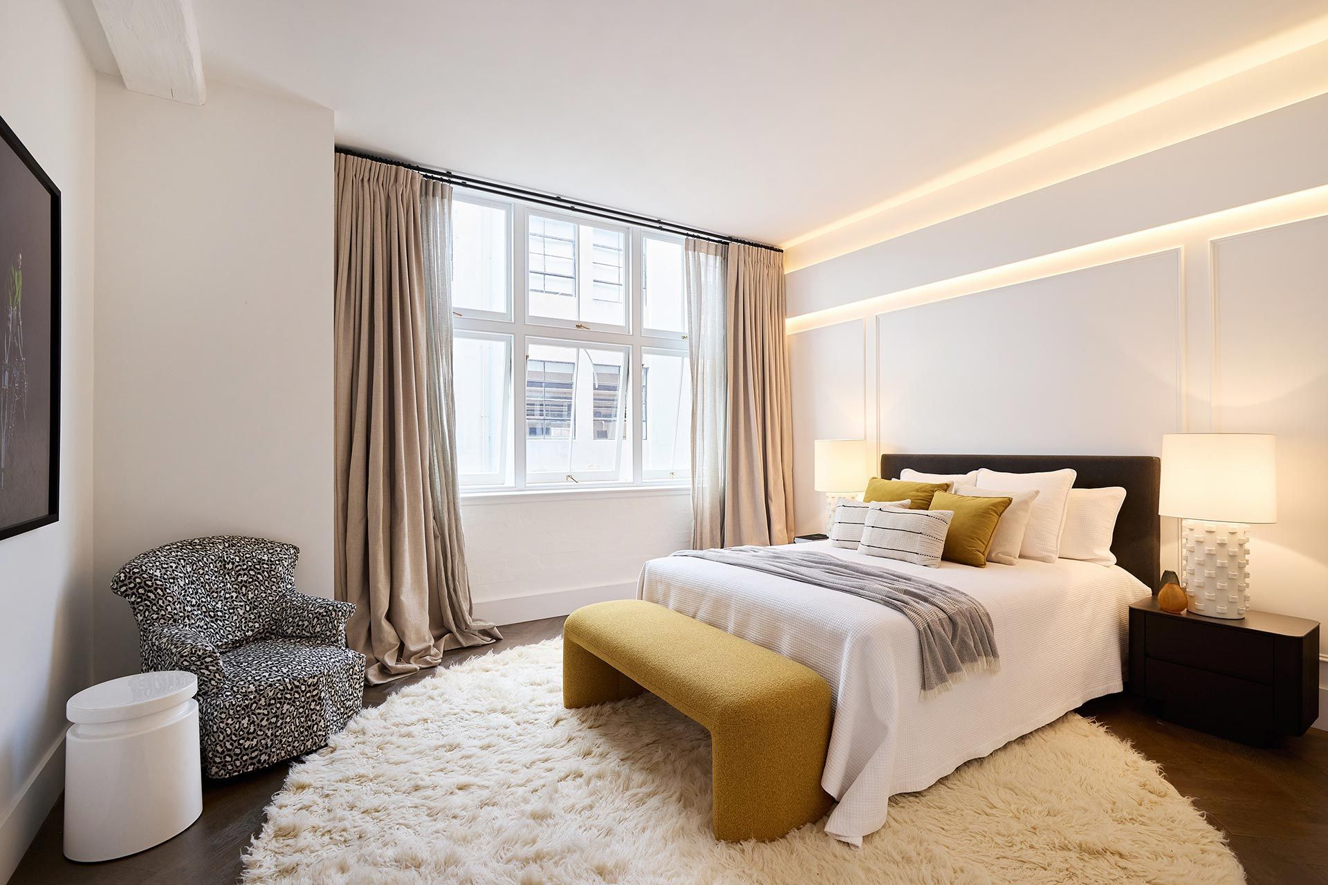 A bedroom with a large bed and a yellow bench