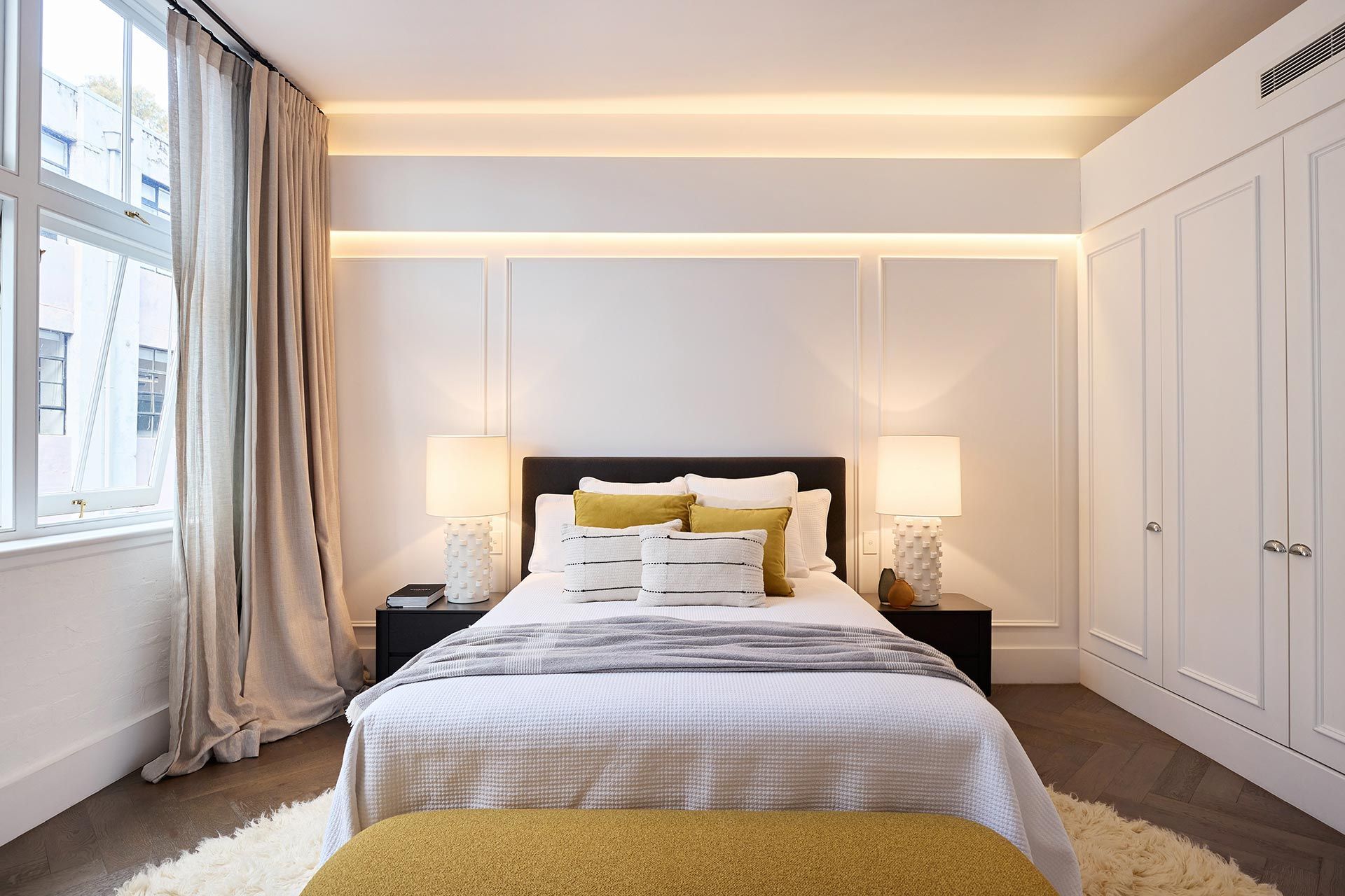 A bedroom with a large bed and a yellow bench