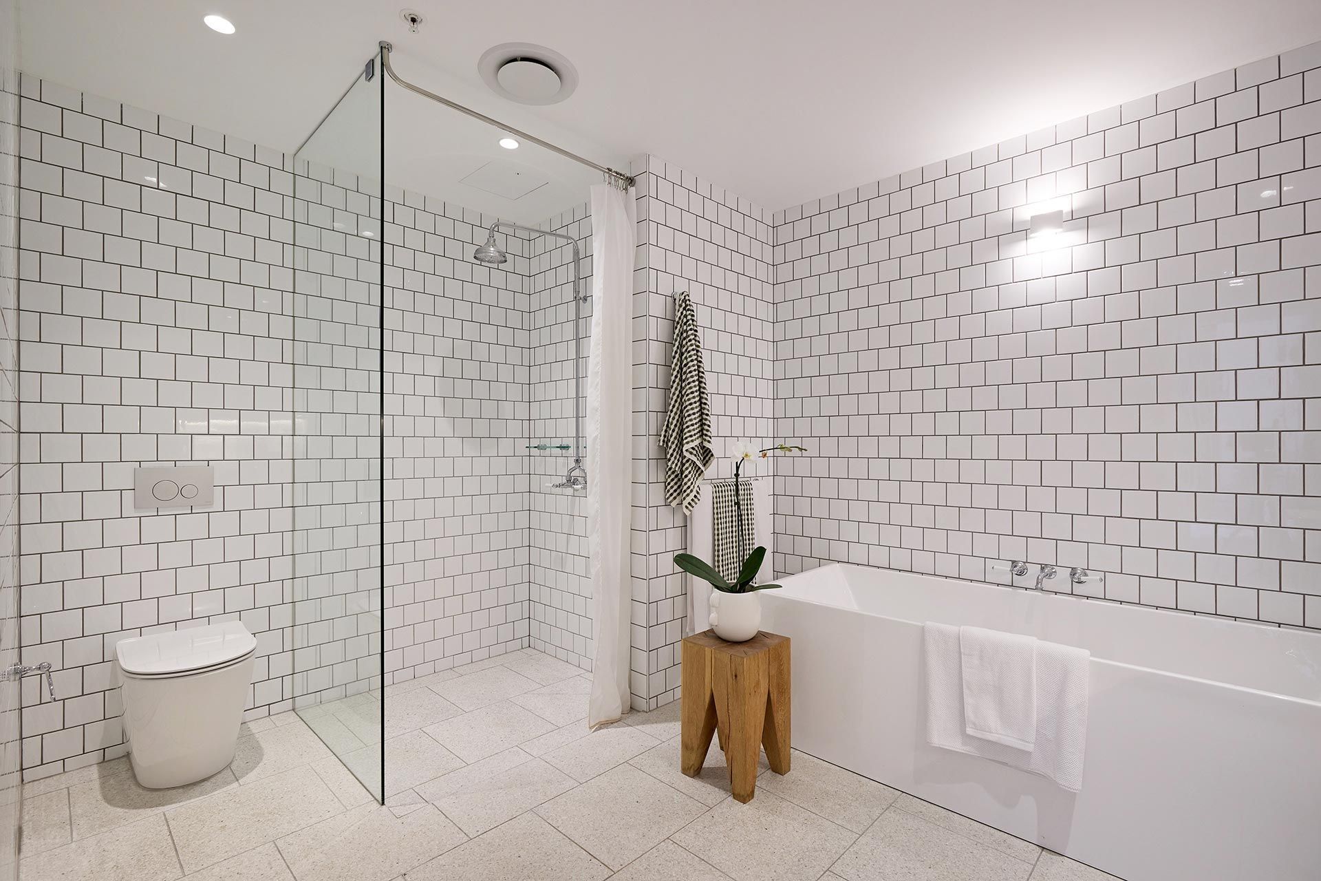 A bathroom with white tiles and a bathtub