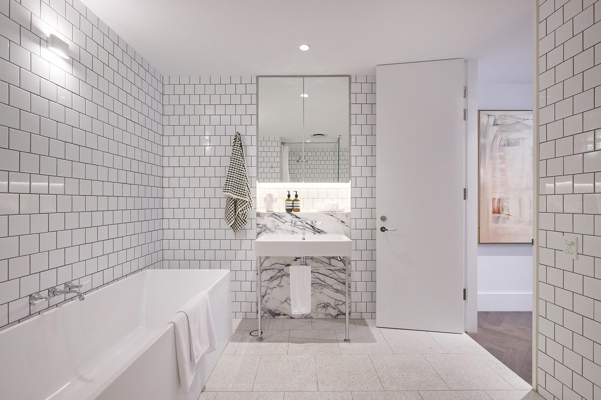 A bathroom with white tiles and a bathtub