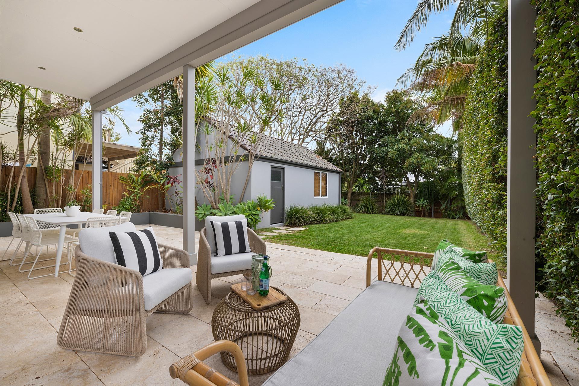 A patio with chairs , a table and a couch in front of a house.