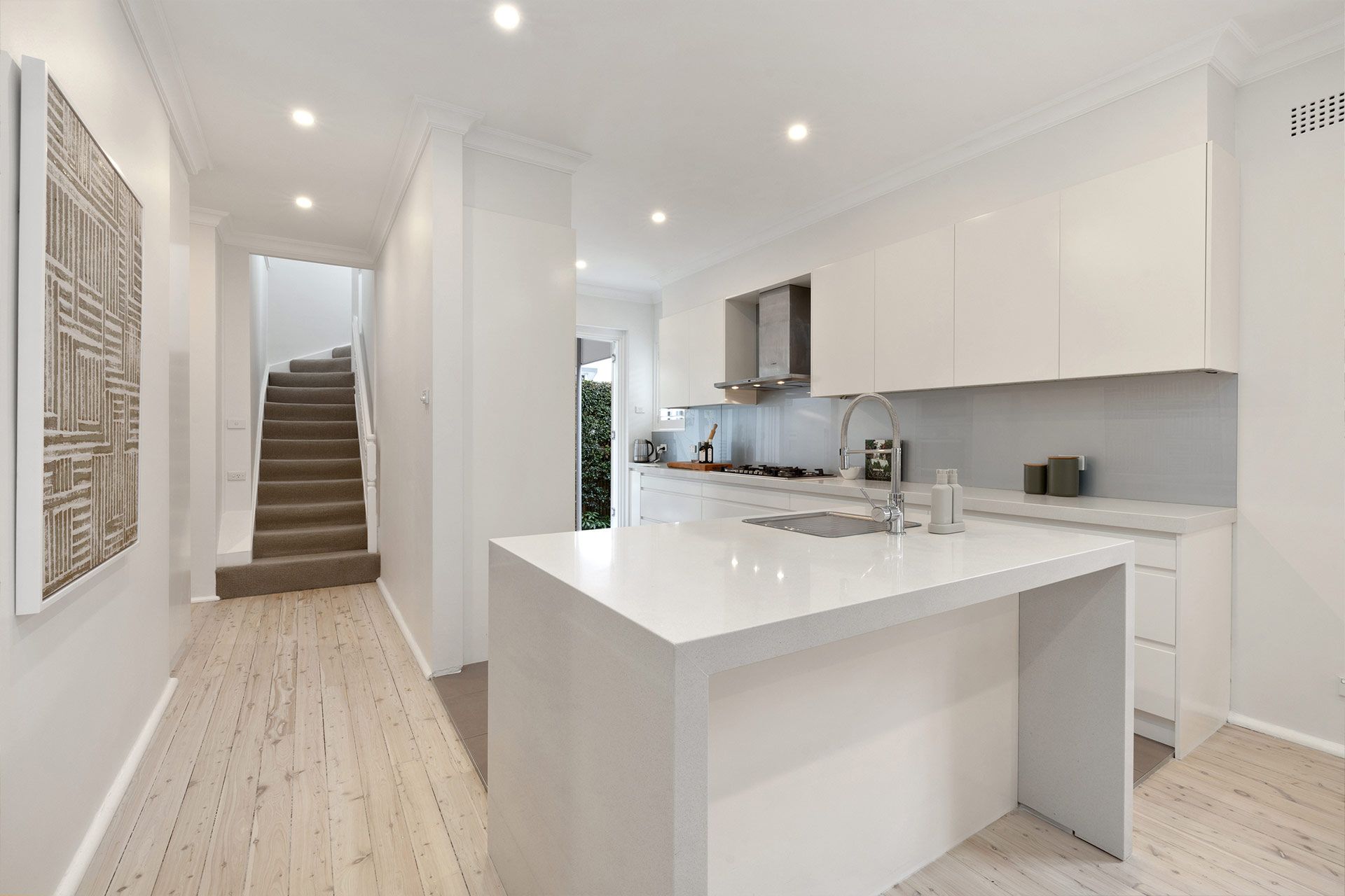 A kitchen with a large island and stairs leading to the second floor.