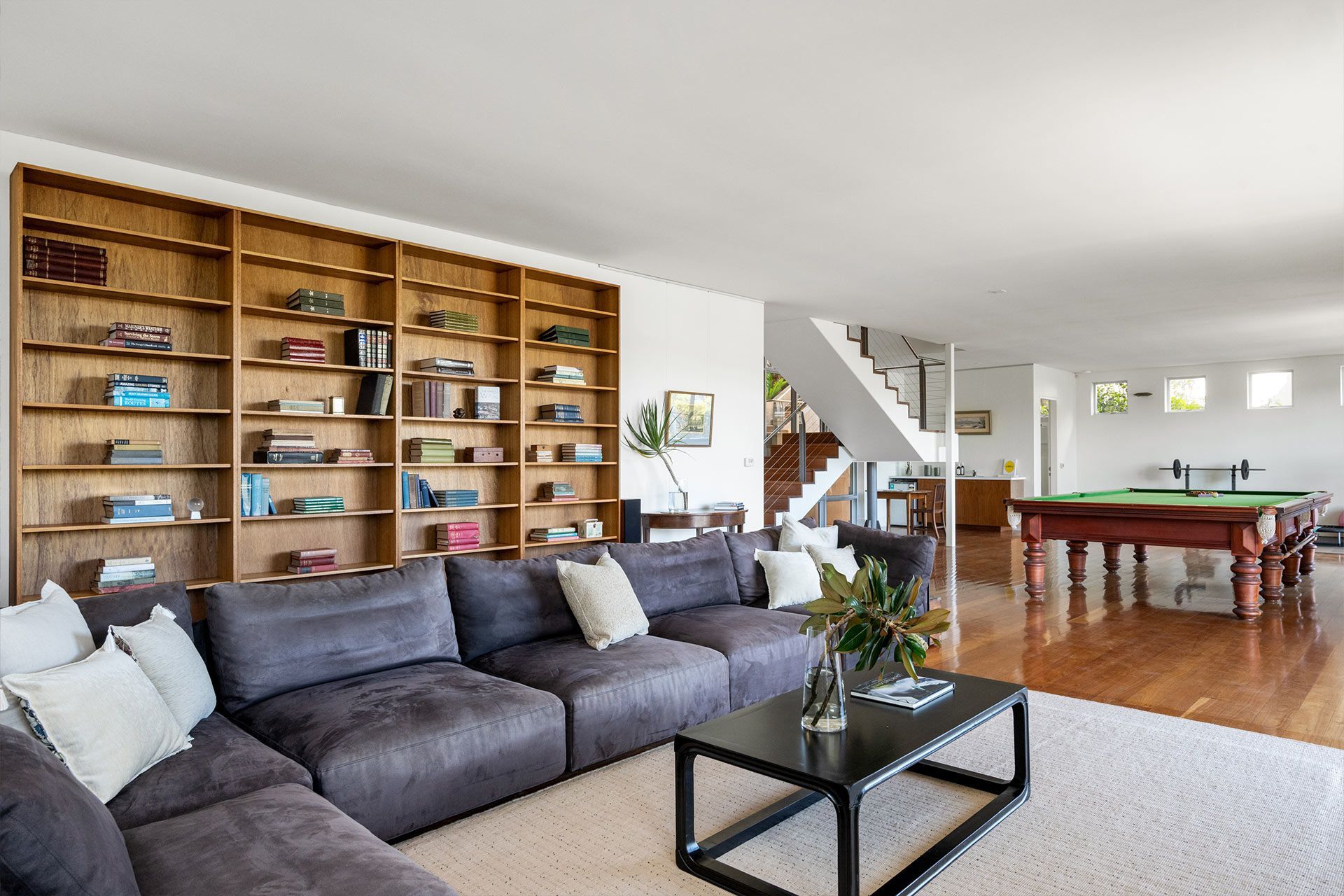 A living room with a large sectional couch and a pool table.
