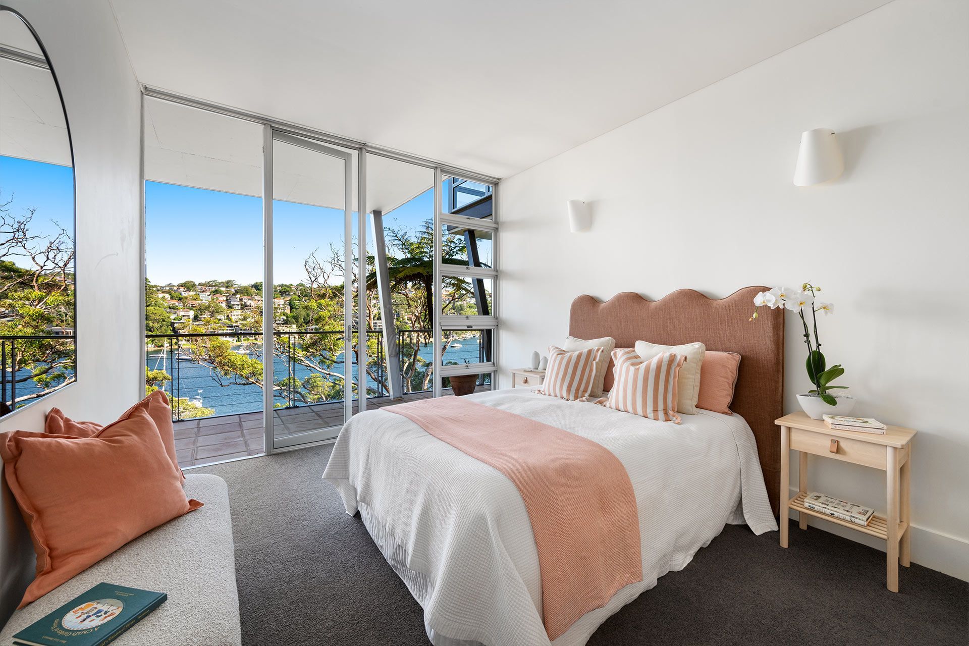 A bedroom with a large bed and a balcony overlooking the water.