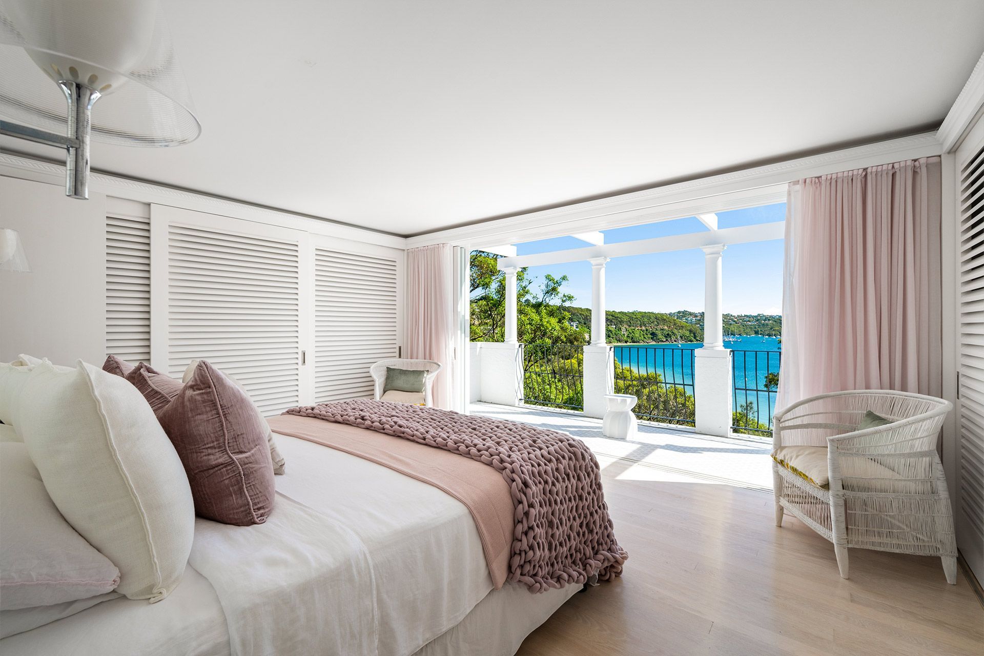 A bedroom with a large bed and a chair with a view of the ocean.