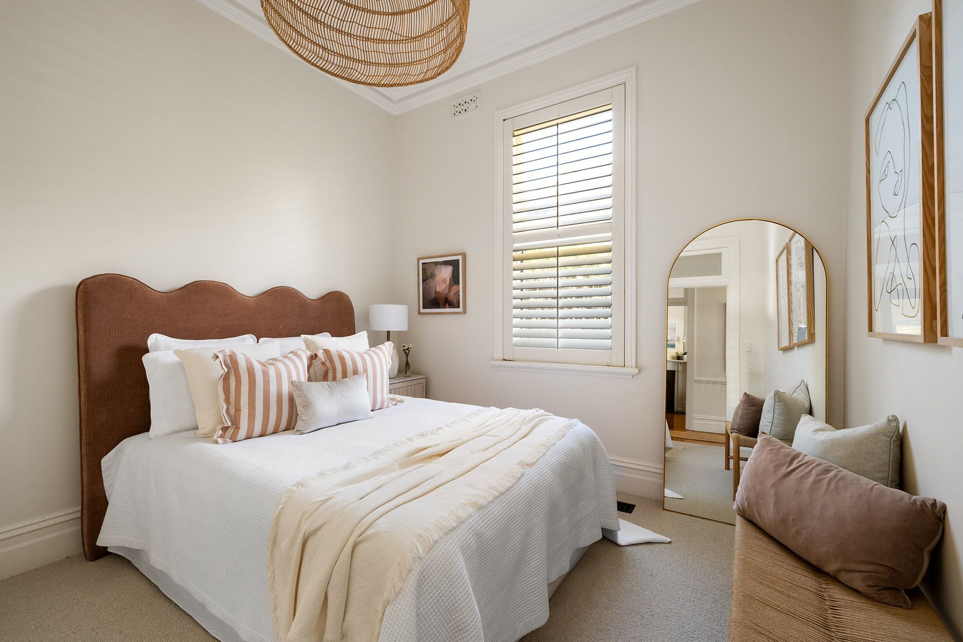 A bedroom with a bed , mirror and window.